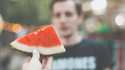 A hand holding a slice of watermelon.